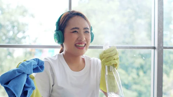 Lykkelig Ung Asiatisk Kvinne Med Hodetelefoner Gummihansker Som Holder Spray – stockfoto