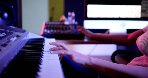 Woman hands on keyboard of piano. Musician woman hands playing piano in studio and purple neon light. Woman pianist