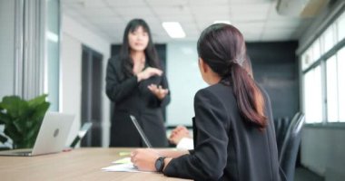 Asyalı kadın çalışanların, meslektaşlarını dinleyen ve pazarlama stratejisini toplantıda açıklayan dikiz görüşü.