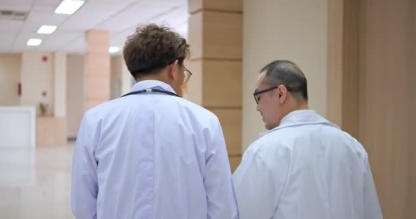 Rückansicht Zwei Seriöse Asiatische Ärzte Gehen Durch Den Krankenhausflur Sie — Stockvideo