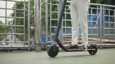 İş için elektrikli scooter kullanan Asya işi şehir merkezinde işe gider. Ekolojik ulaşım kavramı.