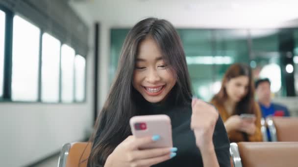 Szczęśliwa Azjatka Pomocą Telefonu Świętując Sukces Online Wygrać Dziewczyna Czyta — Wideo stockowe