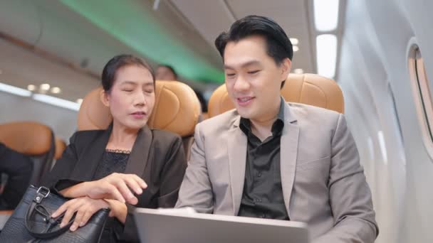 Δύο Επιχειρηματίες Συζητούν Καθίσματα Αεροπλάνων Και Χρησιμοποιούν Φορητούς Υπολογιστές Κατά — Αρχείο Βίντεο