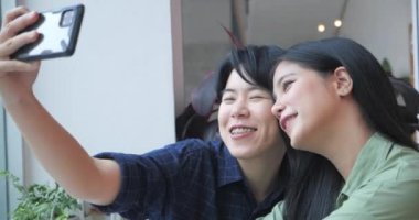 Kafe restoranında akıllı telefondan selfie çeken mutlu bir lezbiyen çift.
