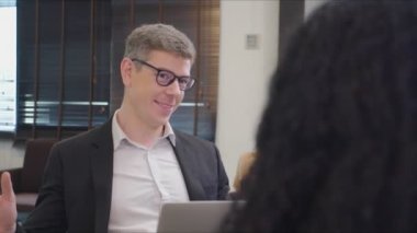 Kendine güvenen iş adamı Afrikalı Amerikalı iş kadınıyla konuşuyor. Çeşitli erkek iş arkadaşları için yeni bir iş konsepti sunuyor. Birlikte dizüstü bilgisayar kullanın
