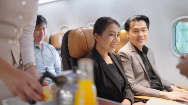 フレンドリーなアジアの女性客室乗務員が飲み物を提供し 飛行機で乗客と話します 航空会社サービス — ストック動画