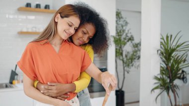 Mutlu lezbiyen çift, evdeki mutfak odasında birlikte yemek pişirirken birbirlerine sarılıyorlar. Lezbiyen çift mutfak odasında sarılıyor. Lgbt ilişki kavramı