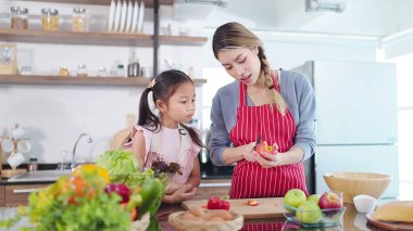 Genç Asyalı anne küçük kızına elma kesmeyi öğretiyor. Sağlık hizmetleri için meyve yiyorum. Mutlu Asyalı aile, sağlıklı gıda konsepti