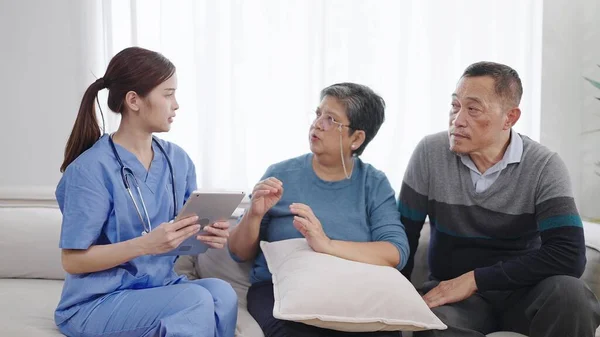 Ασιάτισσα Νοσοκόμα Φροντιστής Περιγράφει Την Κατάσταση Της Υγείας Του Ηλικιωμένου — Φωτογραφία Αρχείου