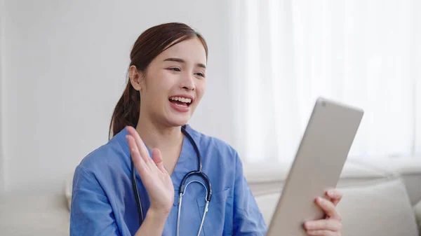 Smiling Young Asian Female Doctor Nurse Waving Hands While Using — Stock Photo, Image