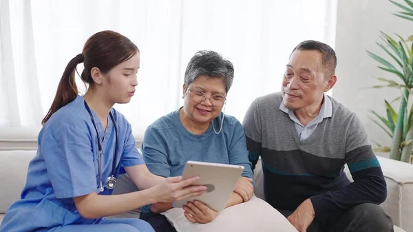 アジアの女性看護師は タブレット上の高齢のカップルの状態の健康を記述しています ホームケア 高齢者介護について 高齢者ケアコンセプト — ストック写真
