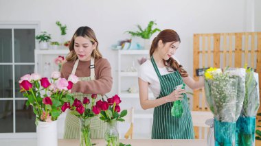 Çiçekçide çalışan iki Asyalı kadın çiçekçi. Çiçekçide çiçek satmak için vazo seçip düzenlemelerine yardım eden iki kadın. Çiçekçi konsepti, küçük işletme sahibi
