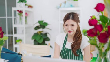 Genç Asyalı güzel kadınların önlüklerinde çiçekçi dükkanı vardı dizüstü bilgisayarda çalışıyorlardı ve çiçekçide müşterileriyle sipariş alıyorlardı. Küçük işletme kavramı