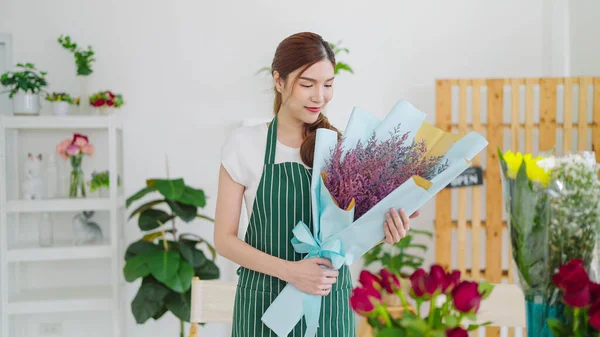 Beautiful asian woman owned of flower shop holding bouquet of flowers. Woman florist holding bouquet of flowers standing at flower shop. Small business concept