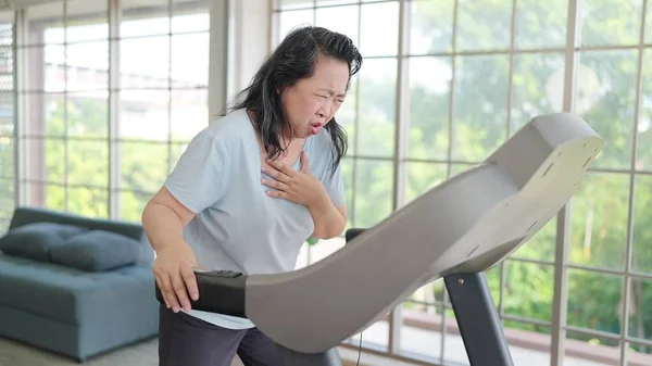 Asian elderly women have chest pain while exercising on the machine at home. Elderly lifestyle, Pain from exercise