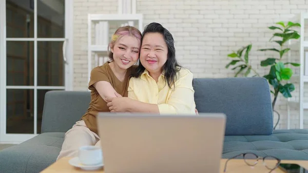 Happy loving elderly Asian mother and daughter laughing embracing, caring spending time together at home. Middle aged mom and daughter hugging. Mother and daughter relationship