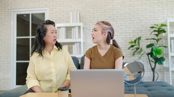 Elderly Asian mother and teenage daughter unhappy and having arguing at home. Elderly mother scolding teenage grown up daughter discontent with behavior bad attitude. Generational gap concept
