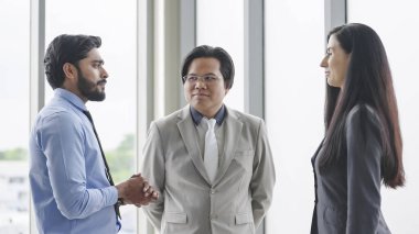 Üç meslektaş ofiste iş hakkında konuşuyor ve tartışıyorlar. Modern ofiste ayakta dikilirken birbirleriyle konuşan bir grup iş adamı. İş toplantısı