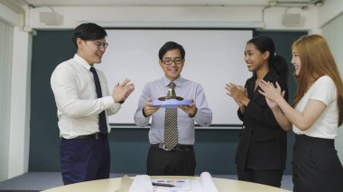 Arkadaş canlısı iş arkadaşları, ofiste buluşurken Asyalı erkek yöneticiye doğum günü pastası verirken sürpriz yapıyorlar. Bir grup Asyalı iş adamı doğum gününü pastayla kutluyor.
