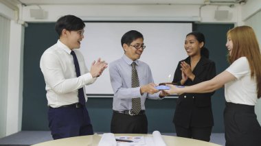 Arkadaş canlısı iş arkadaşları, ofiste buluşurken Asyalı erkek yöneticiye doğum günü pastası verirken sürpriz yapıyorlar. Bir grup Asyalı iş adamı doğum gününü pastayla kutluyor.