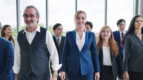 Businesspeople group walking at modern office. Group of diverse colleagues in suit walking together at office. Teamwork and success concept. Multiethnic business people group