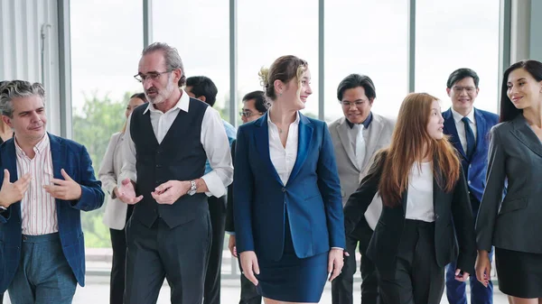 Group of diverse business people talking while walking together at modern office. Group of diverse coworkers discussion while walking the corridor in office together. Multiethnic business people group