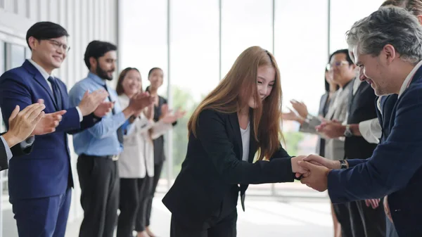 Friendly diverse employees congratulating businesswoman with business achievement. Female manager shakes hands with colleagues on job well done. Group of business people applauding