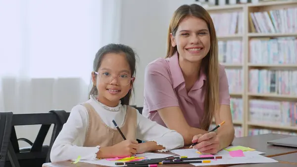 ハッピーな女子高生と若い女性教師が学校の教室でカメラに微笑んでいる 教師の女性と小さな女の子の生徒 学校のコンセプト 学習コンセプトに戻る — ストック写真