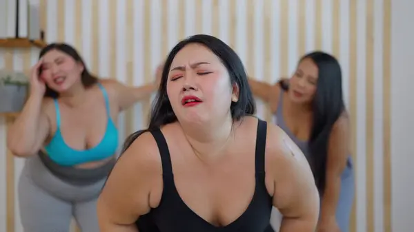 Group of plus size woman friends feeling tired during doing aerobics exercises together. Chubby woman friends feeling exhausted after training workout. Healthy lifestyle concept