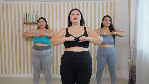 Happy chubby woman friends doing aerobics exercises at home. Group of plus size woman friends in sportswear enjoy aerobics dance together. Healthy lifestyle concept