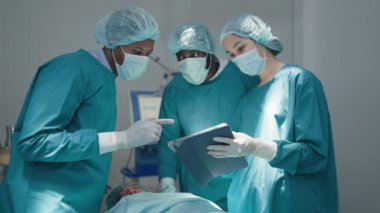 Profesyonel cerrahlar ve asistanlar ameliyat sırasında modern hastane acil servislerinde dijital tablet bilgisayar kullanıyorlar..