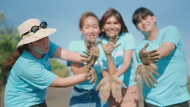 泥の看板に土の手を示すアジアのボランティアのグループは 環境保護と生態系のためのマングローブ林に木を植えるカメラヘルパーを笑顔で見て 地球温暖化を減少させます — ストック動画