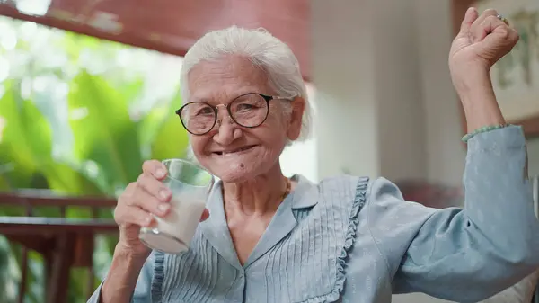Attractive Asian elderly older drink a glass of milk in leisure time at home. Elderly woman drinking fresh milk in the morning for health care. Elderly older healthy lifestyle