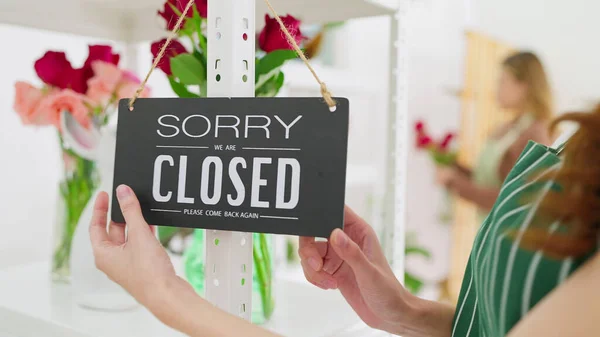 Store owner turning closed sign broad through glass door. Small business owner turning close signboard, sorry. Shop closed. No service business store sign concept
