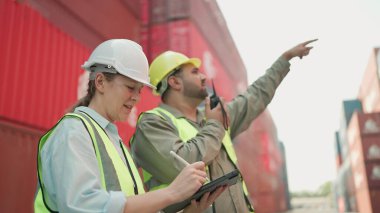Tablet kullanan iki sanayi işçisi konteynır deposunda birlikte çalışıyor. Kargo taşımacılığı ithalat ve ihracat endüstrisi. Lojistik nakliye şirketi. Takım çalışması konsepti