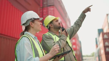 Tablet kullanan iki sanayi işçisi konteynır deposunda birlikte çalışıyor. Kargo taşımacılığı ithalat ve ihracat endüstrisi. Lojistik nakliye şirketi. Takım çalışması konsepti