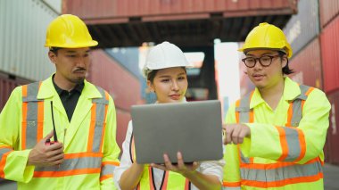 Asyalı endüstriyel mühendisler dizüstü bilgisayarda çalışıyorlar ve kargo konteynır deposundaki konteynırları kontrol ve kontrol etme işlemleri hakkında konuşuyorlar. İçeriye Aktar, Takım çalışması kavramı