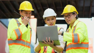 Asyalı endüstriyel mühendisler dizüstü bilgisayarda çalışıyorlar ve kargo konteynır deposundaki konteynırları kontrol ve kontrol etme işlemleri hakkında konuşuyorlar. İçeriye Aktar, Takım çalışması kavramı