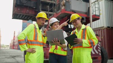 Asyalı endüstriyel mühendisler dizüstü bilgisayarda çalışıyorlar ve kargo konteynır deposundaki konteynırları kontrol ve kontrol etme işlemleri hakkında konuşuyorlar. İçeriye Aktar, Takım çalışması kavramı