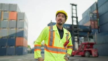 Mühendis ya da üniformalı bir ustabaşı sarı şapkalı bir kontrol konteynırını kargo deposuna yüklüyor. Ulaştırma, İthalat, İhracat, Lojistik Sanayi Hizmetleri