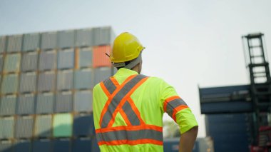 Foreman bir kargo gemisinden konteynır kutularının yüklenmesini kontrol ediyor. Genç ustabaşı iş arkadaşıyla telsiz konuşmasında konuşan konteynırları kontrol ediyor. Kargo sevkiyatı, Lojistik konsept