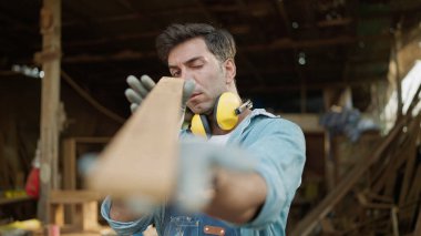 Erkek bir marangoz mobilya fabrikasında ahşap arıyor ve seçiyor. Genç marangoz mobilya atölyesinde şaheser peşinde. Marangoz ve marangoz konsepti