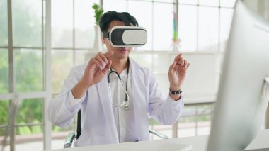 Üniformalı genç Asyalı erkek doktor VR kulaklık ve sanal arayüz takıyor ve havaya dokunuyor. Sağlık hizmetleri kavramında geleceğin tıbbı ve modern teknoloji aletleri