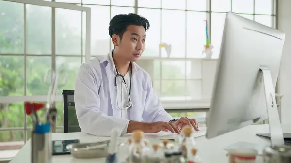 Νεαρός Ασιάτης Γιατρός Χρησιμοποιεί Υπολογιστή Που Δουλεύει Στην Κλινική Στο Εικόνα Αρχείου