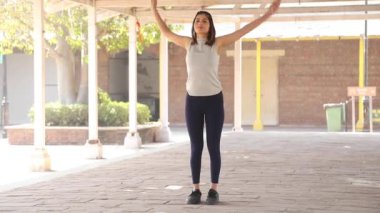 Video of fit woman performing arm rotation exercise, swinging forward and backward her arms.