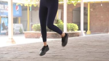 Selective focus of video on woman legs performing butt kicks exercise.