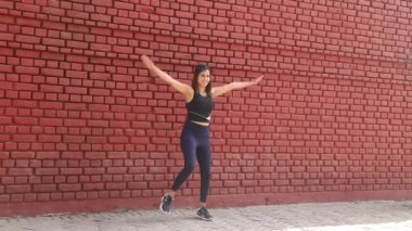 Video of Indian girl in gym suit doing balance and stability of lower body with squat.