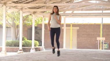 Slim woman performing butt kicks aerobic cardio exercise.