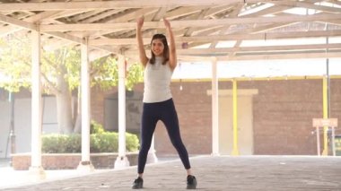 Video of smiling Indian woman performing pull over aerobic cardio workout.