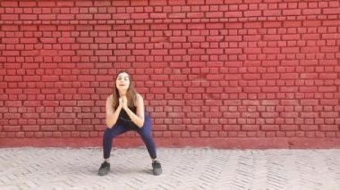 Video of sporty woman in gym suit doing squat and feet together cardio aerobic exercise.